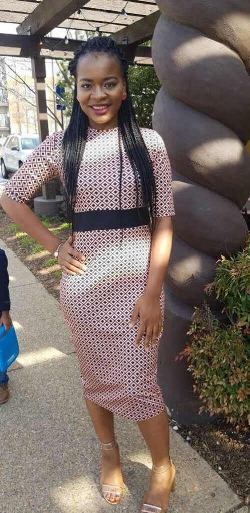 Amie standing in a patterned dress with hand on hip.