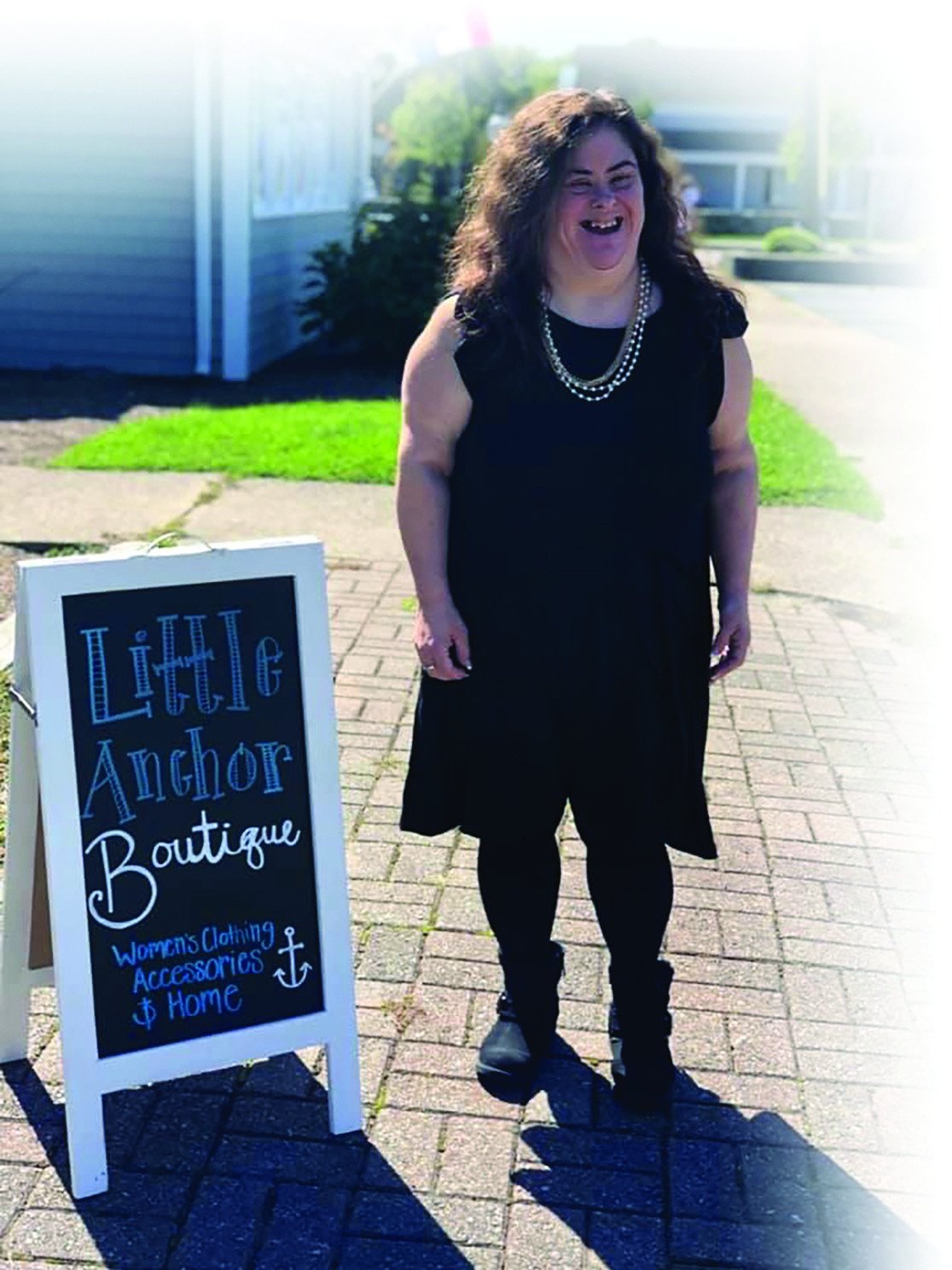 Beth smiling outside a storefront next to a sign reading “Little Anchor Boutique” advertising women’s clothing, accessories, and home goods.